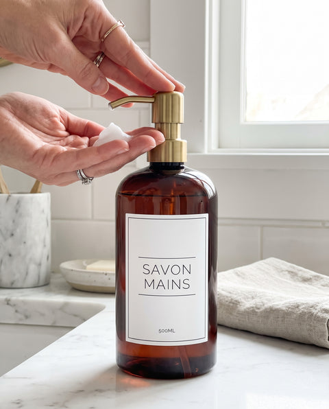 Main qui presse la pompe dorée d'un distributeur Savon mains